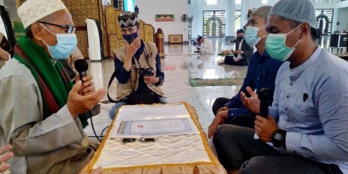 Tangguh Fajar Anugrah (kanan) saat dibimbing KH Abdul Hamid Abdullah, Imam Masjid Nasional Al-Akbar Surabaya, membaca dua kalimat syahadat. foto: mma/ bangsaonline.com