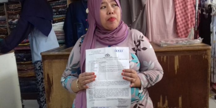 Korban menunjukkan bukti laporan kepolisian.