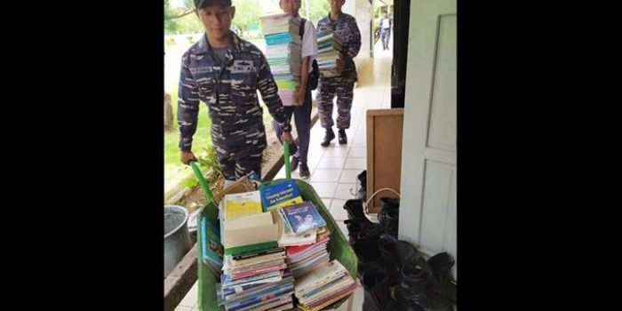 Para Prajurit KRI Yos Sudarso-353 sedang mengangkut ratusan buku ke dalam sekolah.