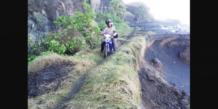 Akibat abrasi, warga melintas di jalan darurat harus dengan hati-hati agar tidak tergelincir.