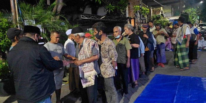 Seorang petugas membagikan sedekah Prof Dr KH Asep Saifuddin Chalim, MA di depan Pondok Pesantren Amanatul Ummah Jalan Siwalankerto Utara Surabaya, Rabu (6/5/2026) malam. Foto: MMA/bangsaonline