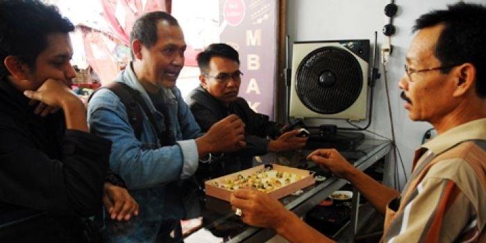 Mbah Kip saat melayani para konsumen emban yang berbahan dari perak di stand pasar induk Bondowoso. foto: Sugiyanto/BangsaOnline.com