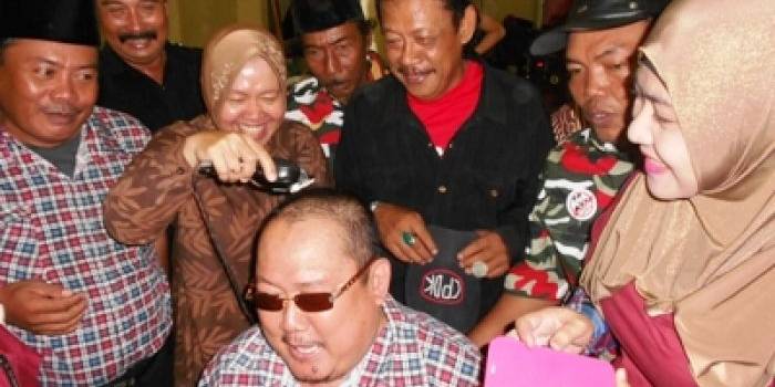 Wali Kota Surabaya Tri Rismaharini mencukur rambut Ketua Umum Gerakan Rakyat Jawa Timur (GRJ), Mat Mochtar, tokoh Madura yang menjadi relawan Jokowi - JK. Foto:diday rosady/BANGSAONLINE