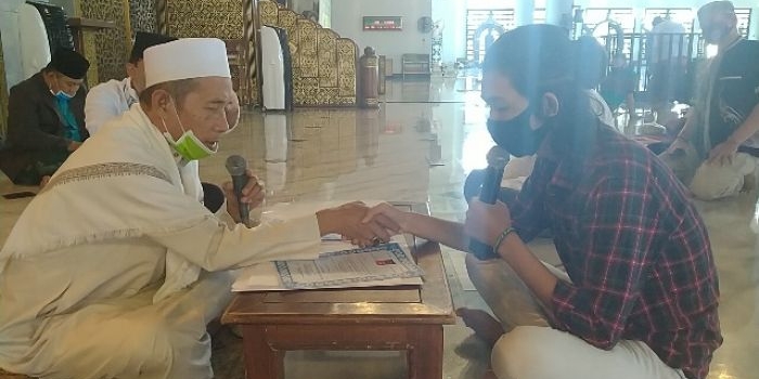 Imam Masjid Nasional Al-Akbar KH Abdul Hamid Abdullah menjabat tangan Bryan Febriyanto saat menuntun ikrar baca dua kalimat syahadat di  Masjid Nasional Al-Akbar, Surabaya, Jumat (10/7/2020). foto: MMA/ bangsaonline.com