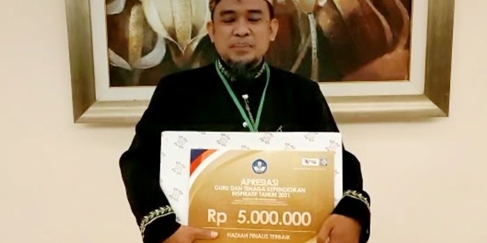 Nono Purnomo, Kepala Sekolah SMP Negeri 5 Kota Mojokerto, menunjukkan Piagam Penghargaan Tenaga Kependidikan Inspiratif dari Kemendikbud Ristek.