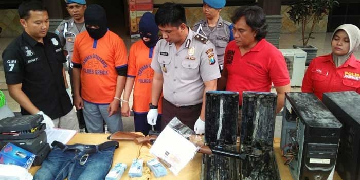 Kasat Reskrim Polres Gresik AKP Adam Purbantoro saat mengekspos kedua tersangka pembobol ATM BNI beserta hasil jarahannya. foto: SYUHUD/ BANGSAONLINE