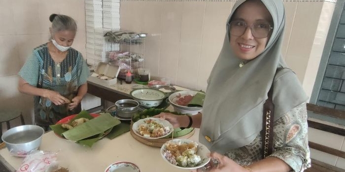 Mbah Riani saat melayani Yunani, salah satu pelanggan Klepon Miroso. Foto: MUJI HARJITA/ BANGSAONLINE