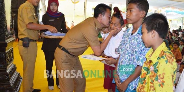 Bupati Jombang, Nyono Suharli Wihandoko bersama Ketua GNOTA Kabupaten Jombang, Tjaturina Wihandoko menyerahkan bantuan biaya pendidikan di Pendopo Kabupaten Jombang, Rabu (28/12). foto: ROMZA/ BANGSAONLINE