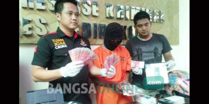 Tersangka bersama barang bukti uang palsu yang tersisa dan beberapa handphone hasil kejahatan saat digelar di Mapolres Kediri Kota. foto: arif kurniawan/ BANGSAONLINE