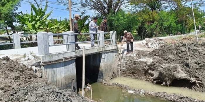 Kades Sekargadung Sumarto bersama tim pelaksana saat meninjau dam pintu air. Foto: Ist