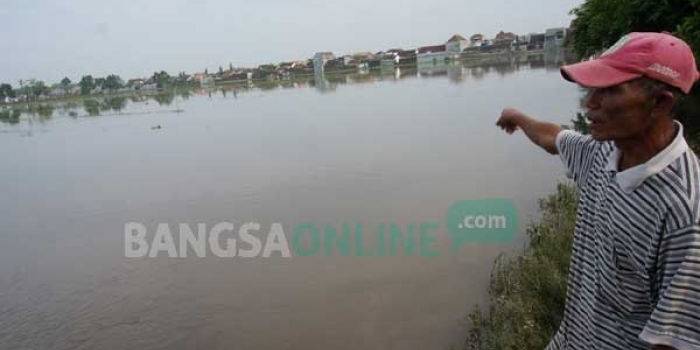 Salah satu petani menunjukkan sawahnya yang terendam banjir. foto: rony suhartomo/ BANGSAONLINE