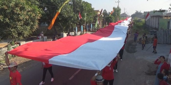 Ribuan Warga membentangkan bendera merah putih keliling kampung. foto: RONY S/ BANGSAONLINE