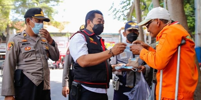 Petugas gabungan saat membagikan makanan pada warga di Jombang.