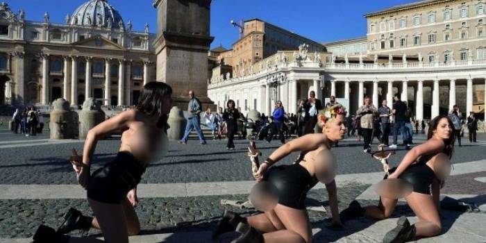 Tiga aktivis femen melakukan demo dengan aksi telanjang sambil menaruh salib di pantat mereka.  Foto: ©AFP PHOTO/ALBERTO PIZZOLI/merdeka.com
