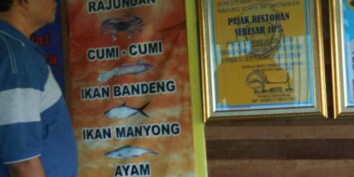Seorang pengunjung sedang melihat pemberitahuan pajak resto.