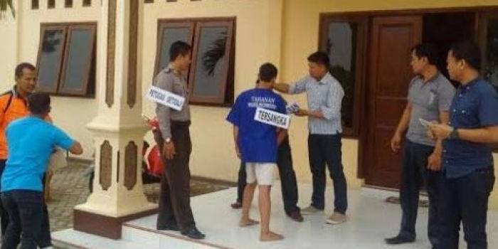 Pelaku saat memeragakan penusukan ketika dilakukan rekonstruksi di halaman Mapolres. foto: beritajatim