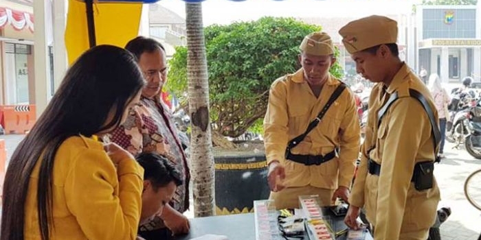 Beberapa polisi berbusana perjuangan tampak sedang melayani masyarakat.