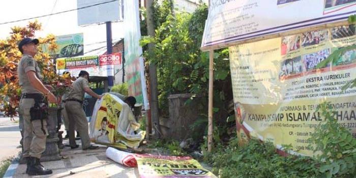 Petugas saat membongkar reklame liar di salah satu sudut jalan. foto: FERI W/ BANGSAONLINE