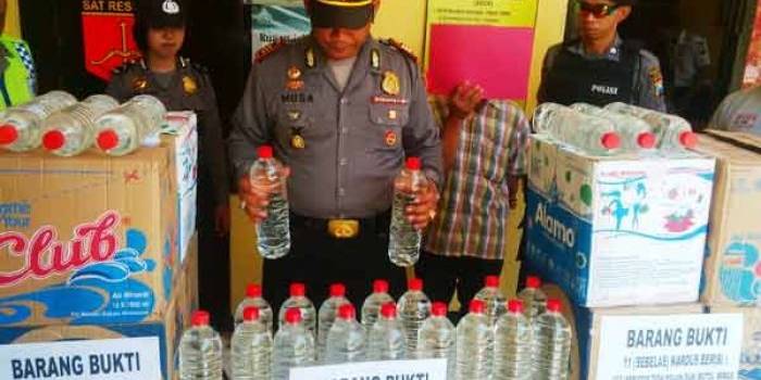 Kapolsek Rengel, AKP Musa Bachtiar ketika memamerkan hasil tangkapan ratusan liter arak. (foto: suwandi/BANGSAONLINE)