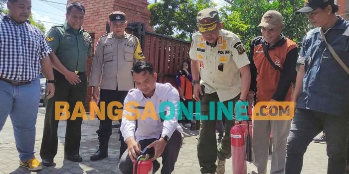 Lurah Gunung Gedangan, Andika (kemeja putih), dan Kepala Satpol PP Kota Mojokerto, Modjari,  saat memadamkan kobaran api dalam simulasi penanganan kebakaran. Foto: YUDI EKO PURNOMO/BANGSAONLINE