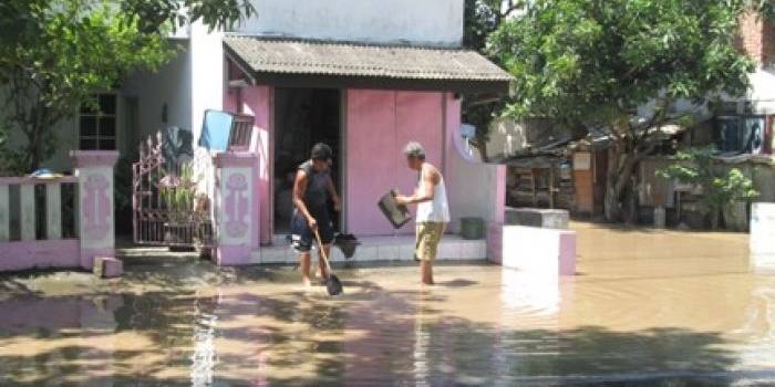 TERGENANG – Warga perumahan di kawasan Kota Madiun membersihkan lingkungan rumahnya yang tergenang air banjir, Rabu (25/3). Foto: hendro/BANGSAONLINE