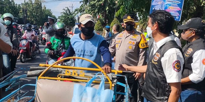 Kapolres Kediri Kota AKBP Wahyudi dan Sunardi dari HDCI Jawa Timur saat membagikan paket sembako kepada abang becak yang melintas di depan Mapolres Kediri Kota. foto: MUJI HARJITA/ BANGSAONLINE