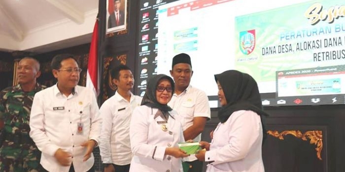 Bupati Jombang Hj Munjidah Wahab menyerahkan buku rekening kas desa kepada dua kades.