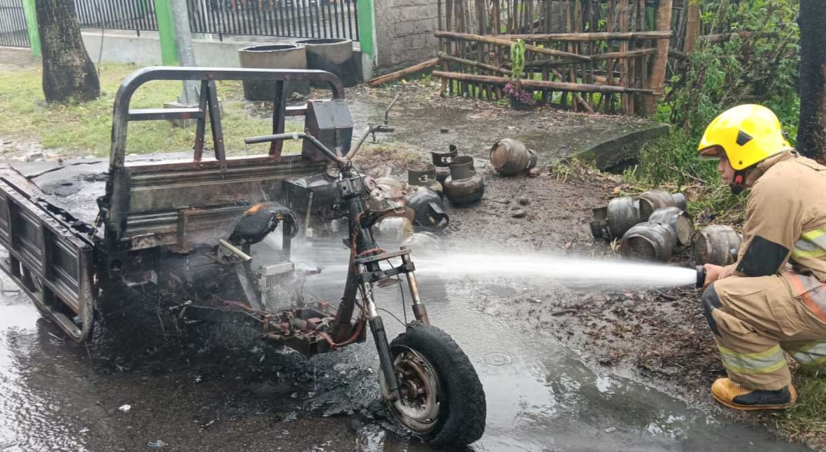 Petugas saat memadamkan api yang membakar kendaraan roda tiga. Foto: Ist

