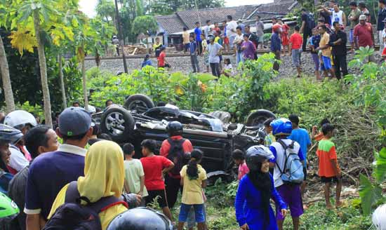 Mobil Daihatsu Terios yang hancur setelah diseruduk kereta api jadi tontonan warga. (foto: tri susanto/BANGSAONLINE)