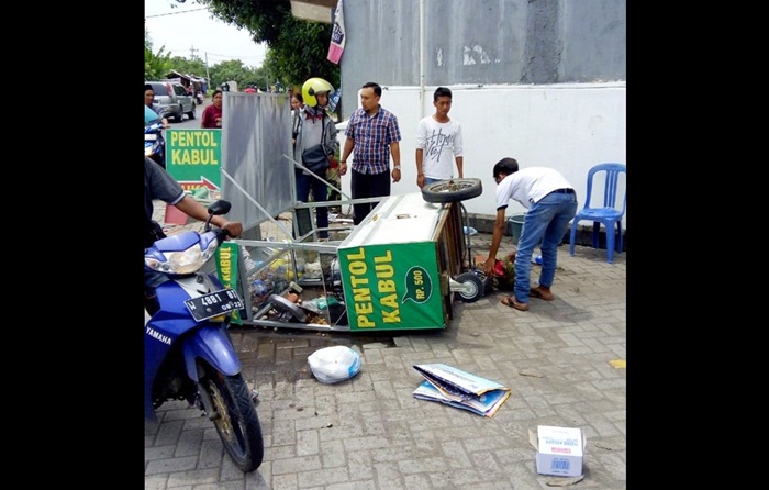 Rombong penjual pentol yang jatuh berserakan serta kacanya pecah, usai digulingkan oleh seorang pria berambut gondrong.