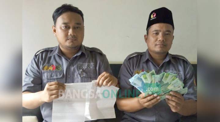 Petugas Bawaslu menunjukkan barang bukti uang beserta lembaran daftar penerima. foto: NOVIAN/ BANGSAONLINE