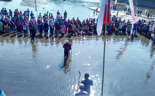 Warga RW 02 Kelurahan Rogotrunan saat menggelar upacara bendera di tengah Kali Asem yang sedang surut airnya. foto: BANGSAONLINE