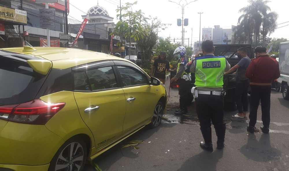 Petugas kepolisian saat mengevakuasi mobil yang tersangkut di median Jalan Pahlawan, Sidoarjo.