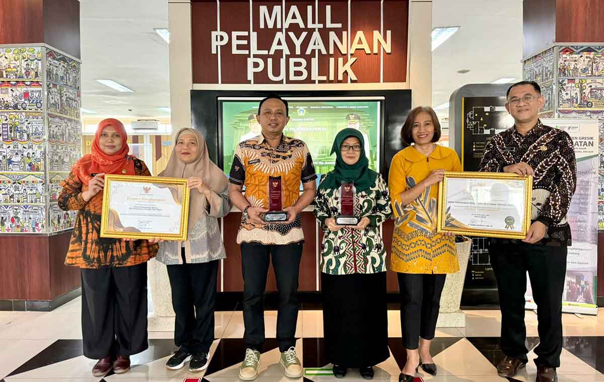 Kepala DPMPTSP Gresik, Agung Endro Dwi Setyo Utomo (tengah), bersama para pejabat menunjukkan penghargaan zona integritas. Foto: Ist