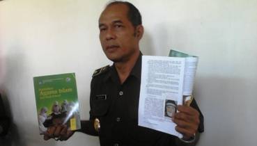 Kasi Intel Kejaksaan saat menunjukkan salah satu halaman buku Agama Islam yang kata-katanya dinilai mengandung ajaran radikal. (Arif Kurniawan/BANGSAONLINE)