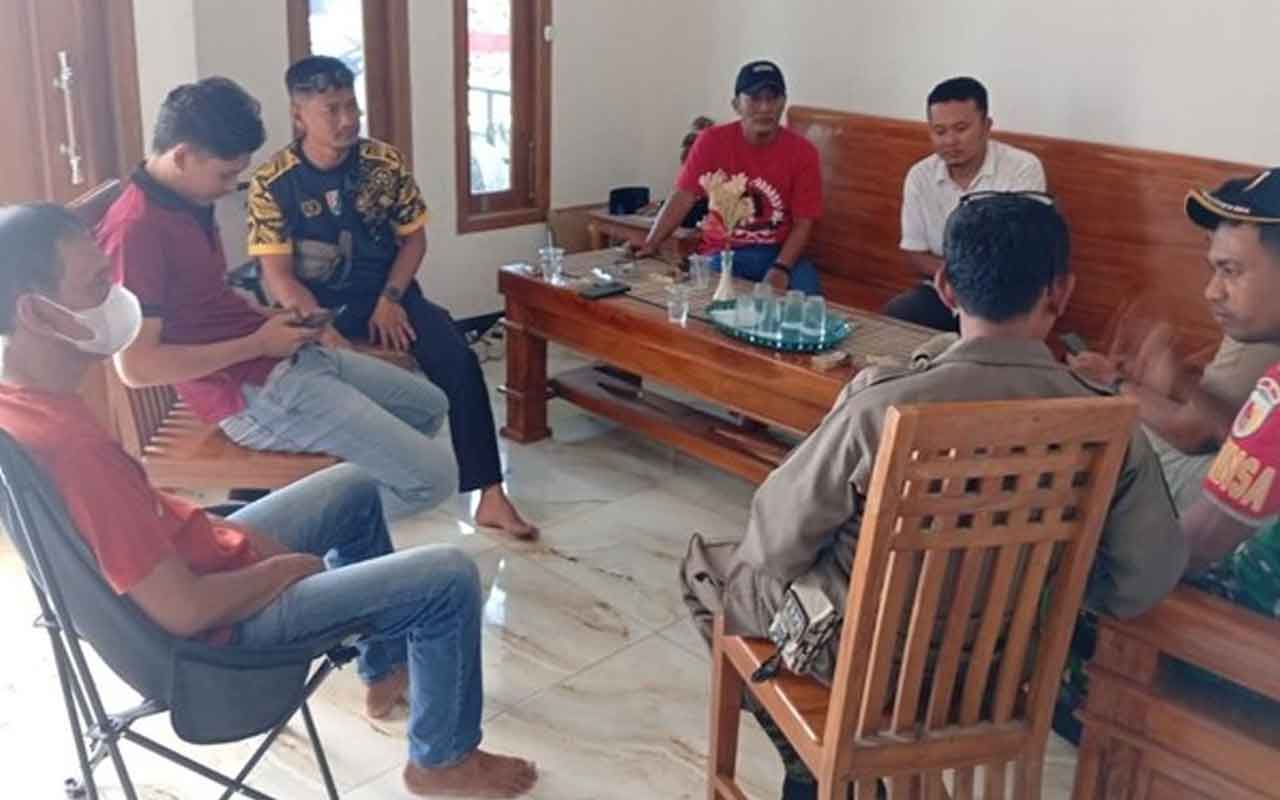 Pria Tuban pengunggah foto hormat ke bendera One Piece (kaus merah pegang HP) saat didatangi aparat gabungan. Foto: Ist.