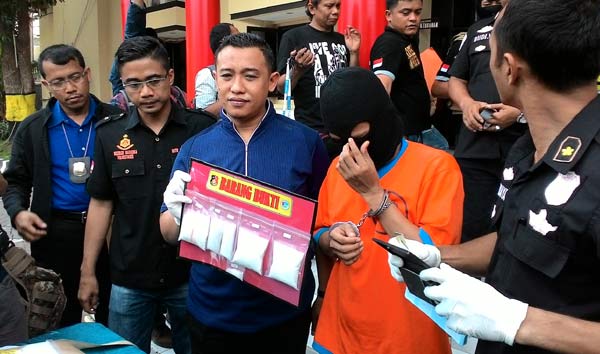 Tersangka Januar beserta barang bukti yang berhasil diamankan polisi. foto: ekoyono/ BANGSAONLINE