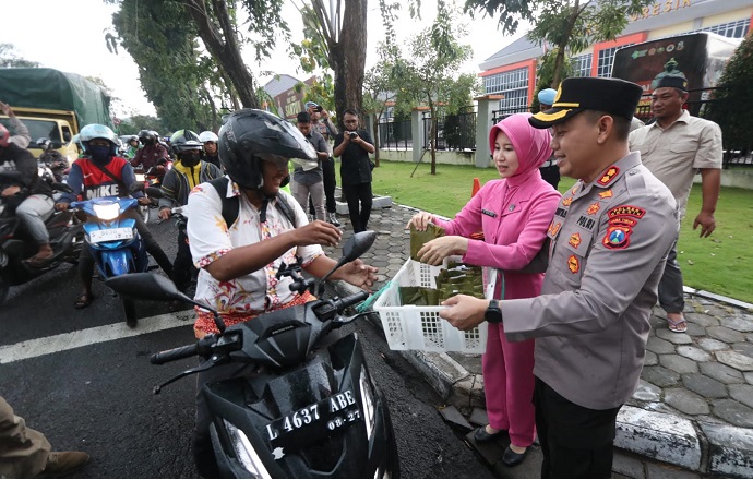 Kapolres Gresik, AKBP Adhitya Panji Anom bersama istri saat bagi-bagi takjil kepada pengguna jalan. Foto: SYUHUD/ BANGSAONLINE.com
