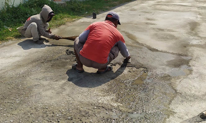 


Sejumlah pekerja melakukan penambalan jalan yang rusak.