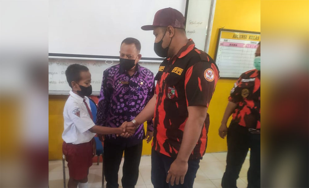 Wakil MPC Pemuda Pancasila Sidoarjo, Andry Harmoko, memberikan bingkisan dan beasiswa kepada Fadil.