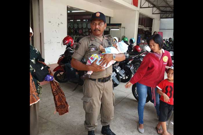 Petugas Satpol PP saat menggendong bayi yang dibawa pengemis untuk diamankan. foto: ist