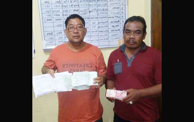 Petugas menunjukkan buku rekapan togel dan uang taruhan. 