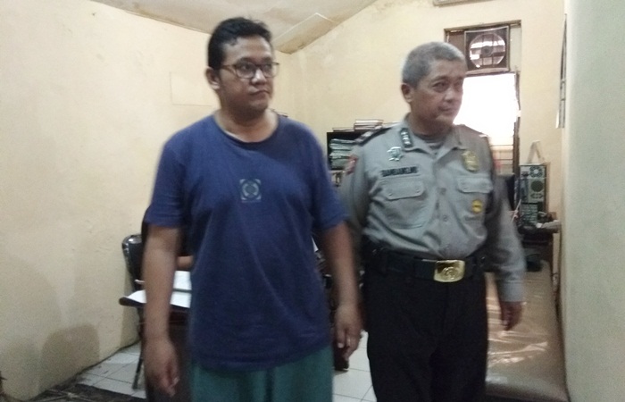 Tersangka pakai kaos biru didampingi petugas.
