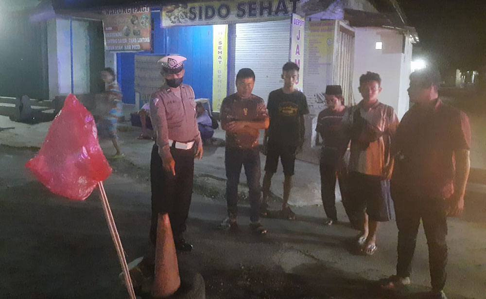 Petugas menunjukkan lubang jalan di sekitar Pasar Nglegok yang jadi penyebab kecelakaan.