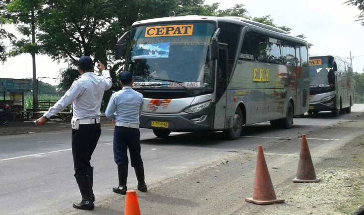 Petugas Dinas Perhubungan mengarahkan bus patas untuk masuk ke dalam terminal. Foto: zainal abidin/ BANGSAONLINE