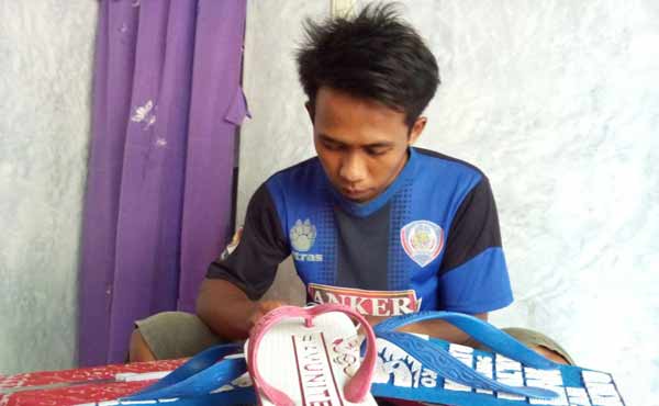 Wahyu saat sedang menggarap sandal jepit karyanya. foto: zainal abidin/BANGSAONLINE