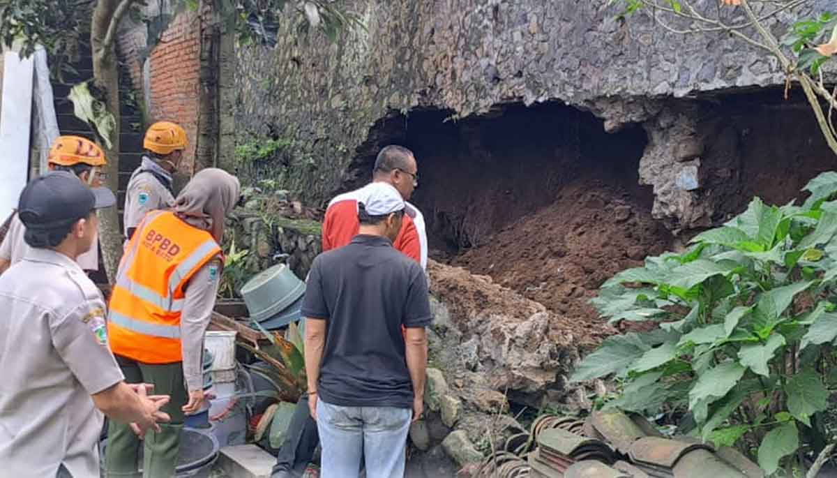 Personel BPBD Kota Batu saat menangani plengsengan rumah yang tergerus akibat curah hujan tinggi.