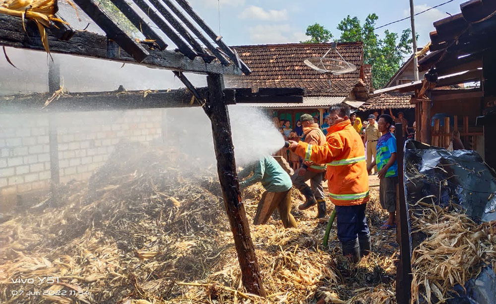 Petugas Damkar Tuban saat melakukan pembasahan terhadap tumpukan jerami yang terbakar.