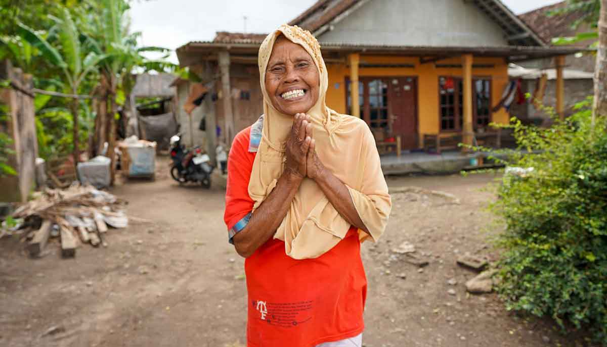 Boniyem (73) tersenyum bahagia setelah mendapat bantuan bahan bangunan semen dari SIG untuk memperbaiki rumahnya yang rusak akibat gempa. Foto: Ist
