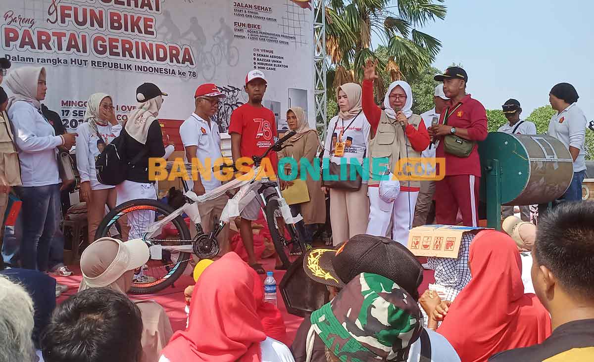 Anggota DPR RI dari Gerindra, Hilmi, didampingi Sekretaris DPC Gerindra Gresik, Nur Saidah, saat menyerahkan hadiah sepeda ontel kepada peserta jalan sehat yang beruntung. Foto: SYUHUD/BANGSAONLINE